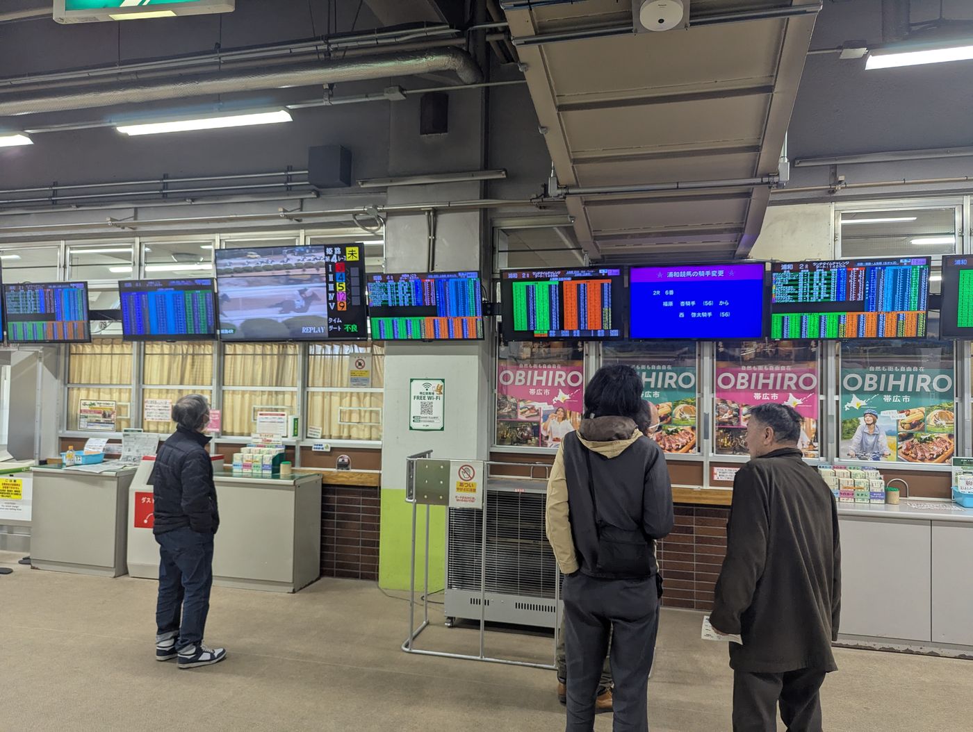開催のない日のばんえい競馬場で、地方競馬のモニターを見ながら馬券を買う来場者たち