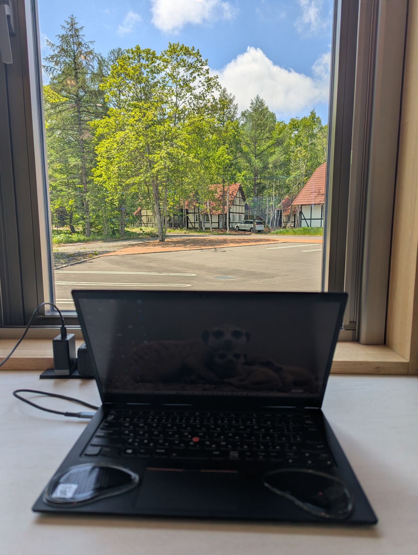 十勝エアポートスパそらの窓際席で、外の緑と青空を眺めながらノートPCでノマドワークをしている様子。
