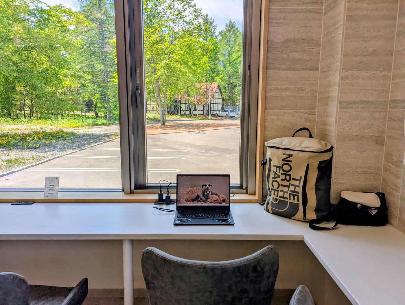 十勝エアポートスパそらの休憩所で、窓の外の緑を眺めながらノートPCで作業する様子。